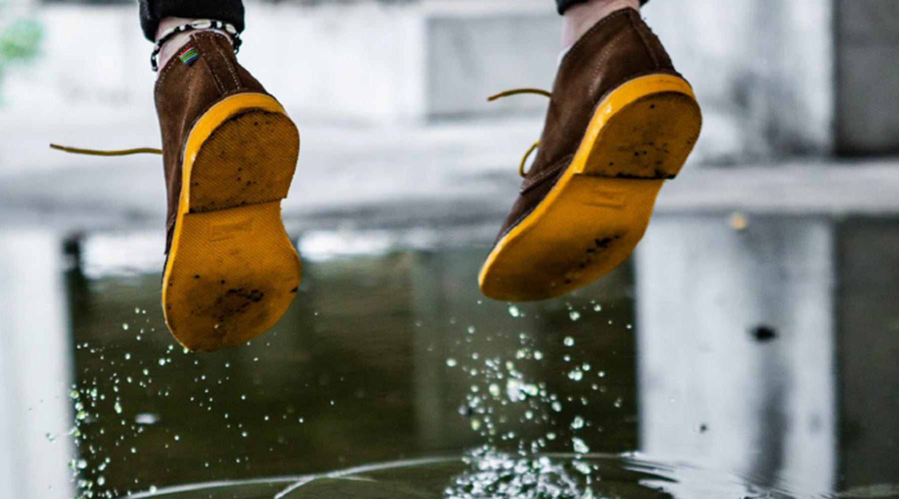 Vellies with yellow soles jumping in puddle. Veldskoen jumping in puddle.