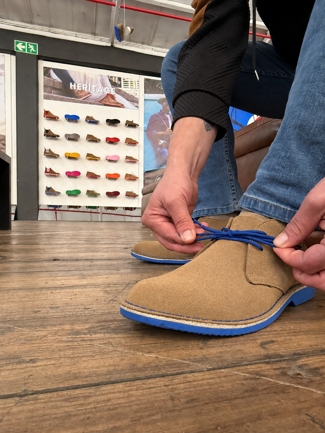 Lacing up a pair of Veldskoen® in front of the Heritage wall